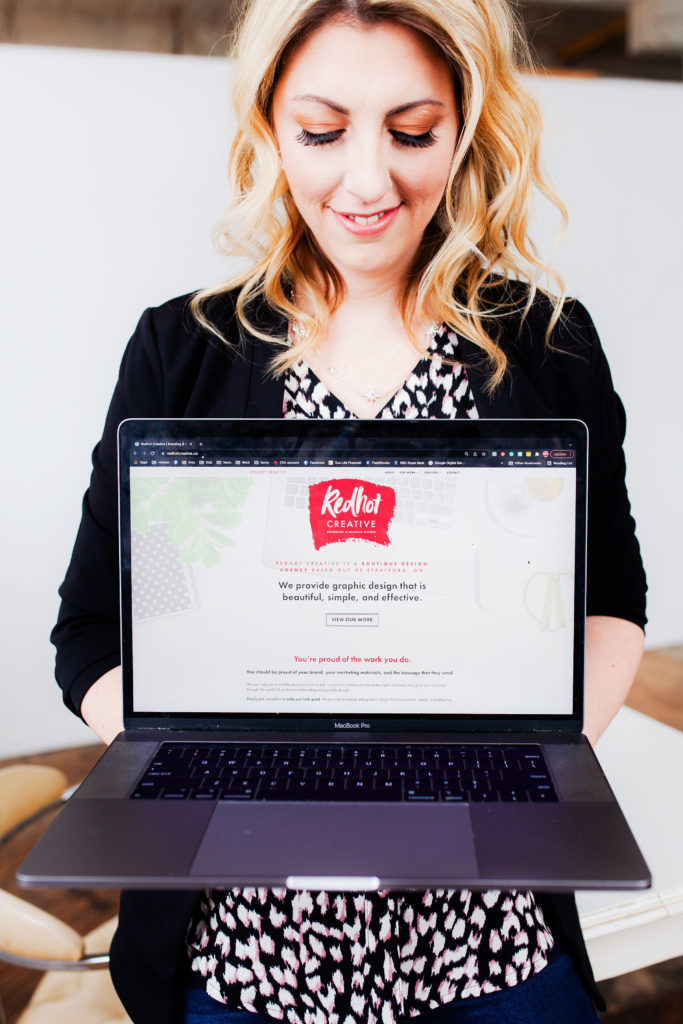 A Blonde Woman (Amy Bannon) using a Macbook Laptop computer to do graphic design and marketing work
